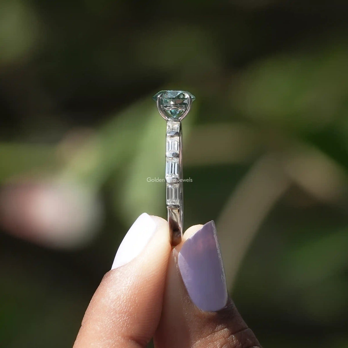 Side View of Green Round Cut Accent Engagement Ring In two fingers