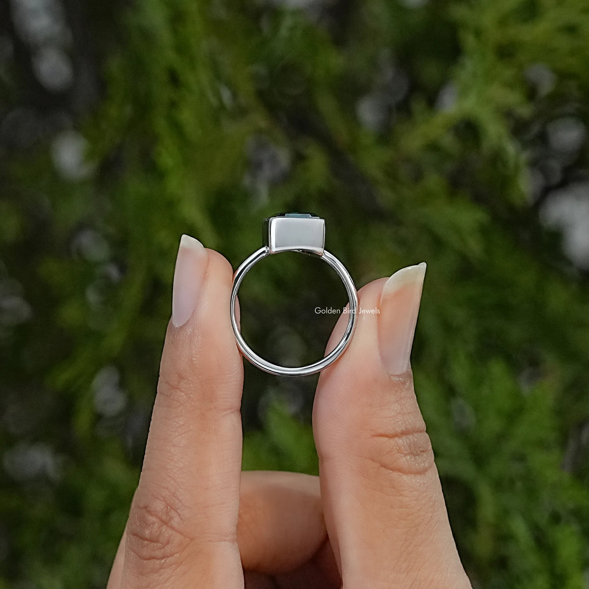 Silver solitaire ring viewed from the back, showing the circular band and raised bezel setting