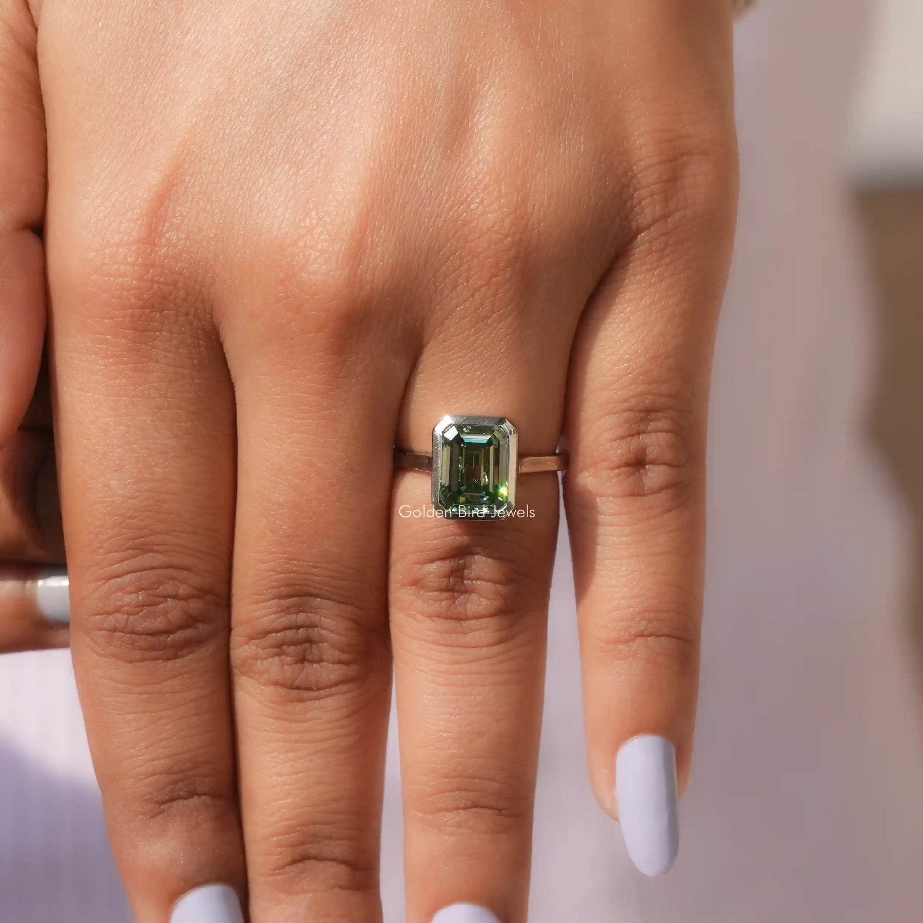 Close-Up View Of Green Emerald Cut Solitare Ring In a White Gold