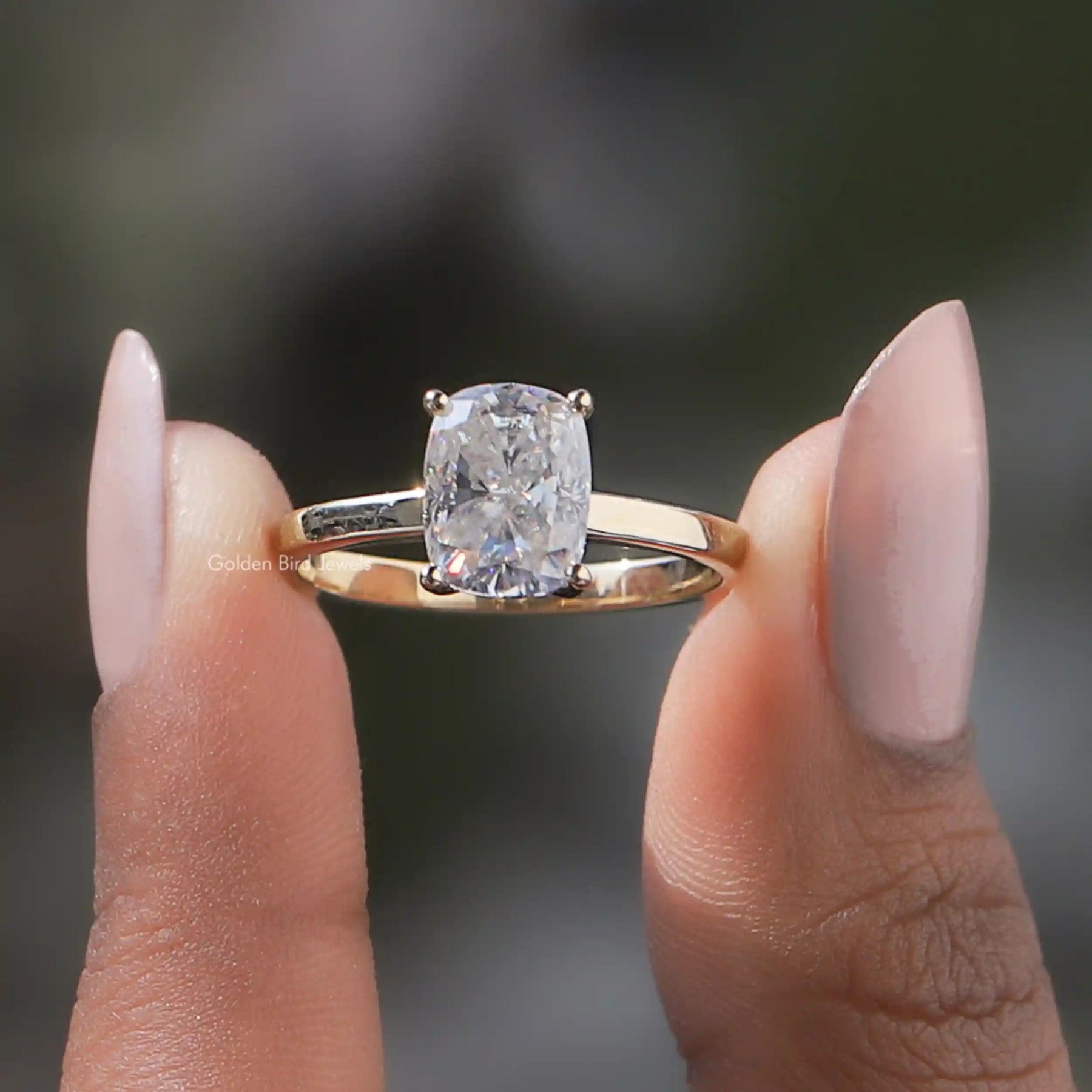Two fingers holding the Cushion Cut Moissanite Ring