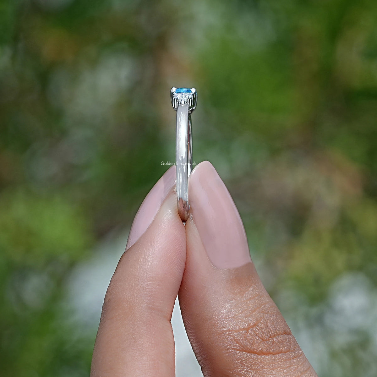 Side View of Oval Cut Gemstone Ring In two fingers
