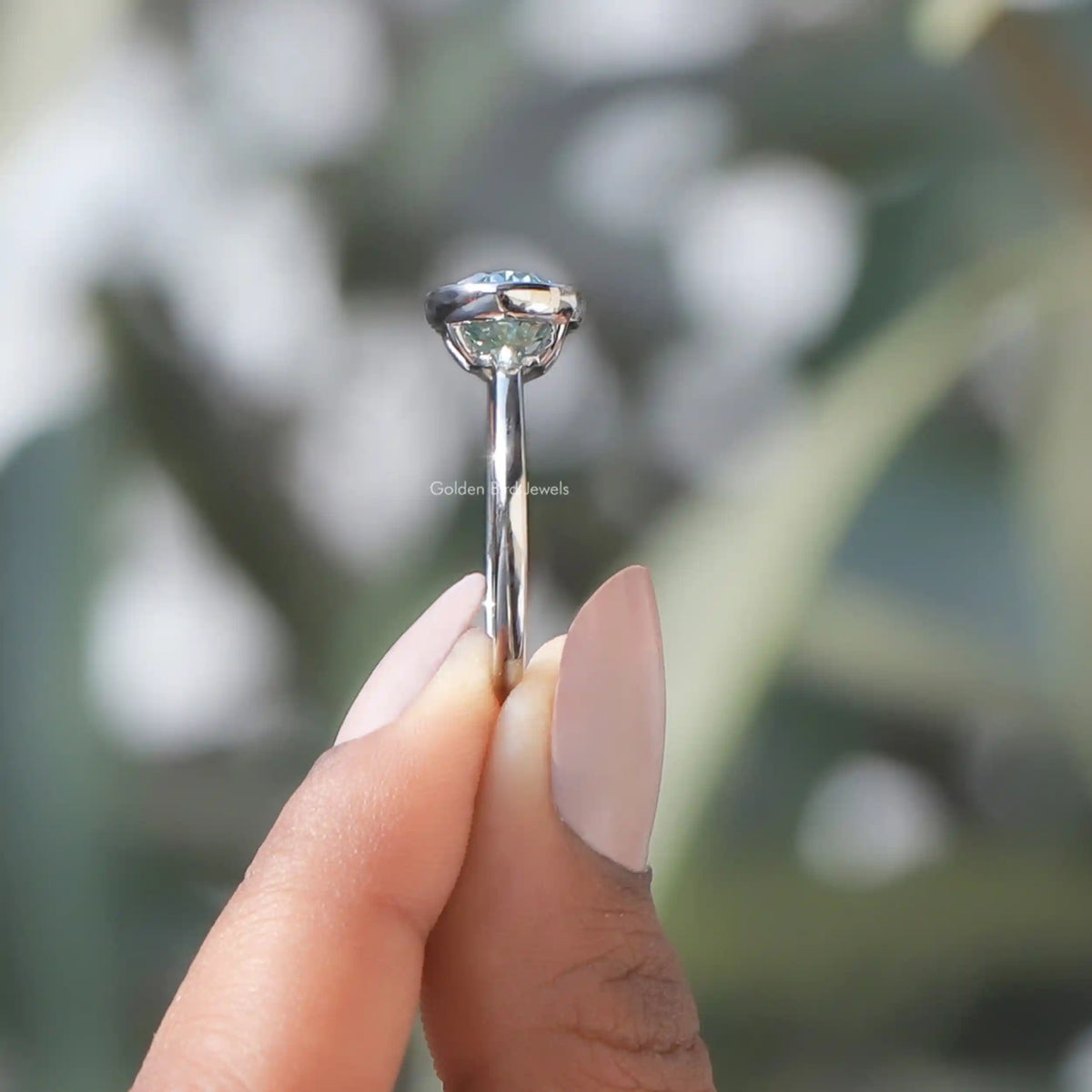 Side View of Moissanite East West Oval Cut Solitaire Ring In two fingers