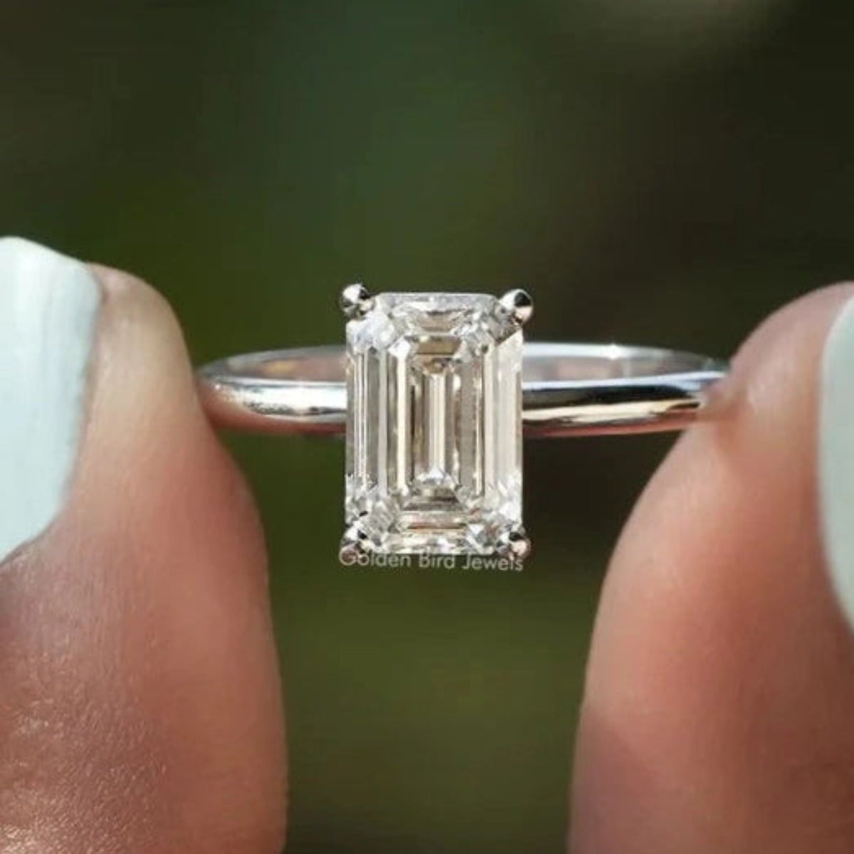 Two fingers holding the Emerald Cut Solitaire Diamond Engagement Ring
