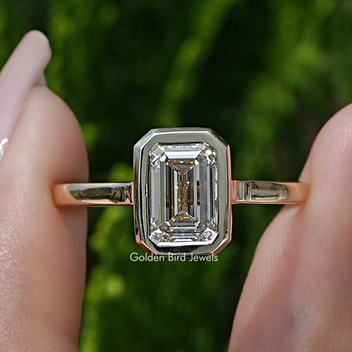 Emerald Lab Diamond Bezel Set Engagement Ring Held Between Fingers