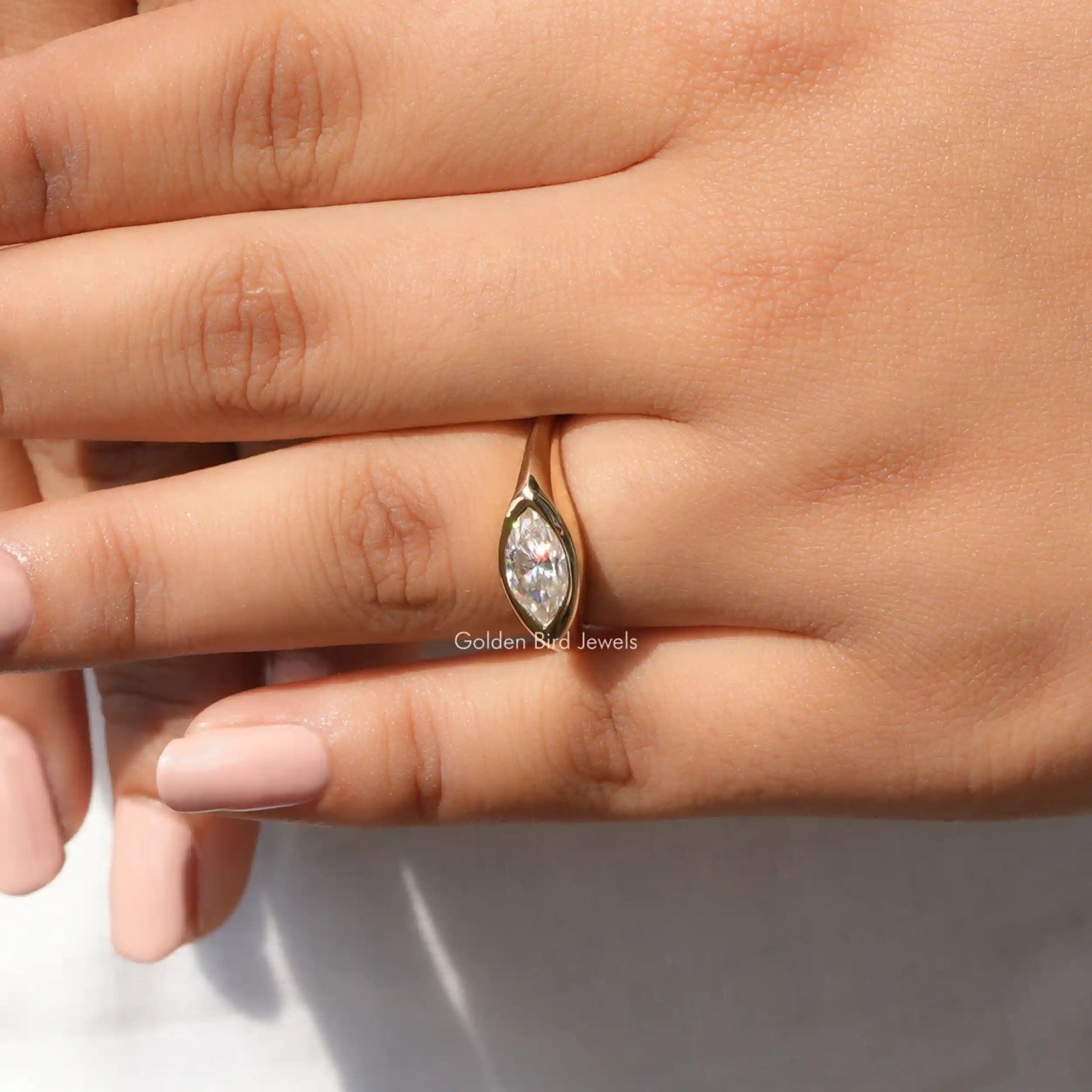 In finger front view of halo moissanite engagement ring in yellow gold