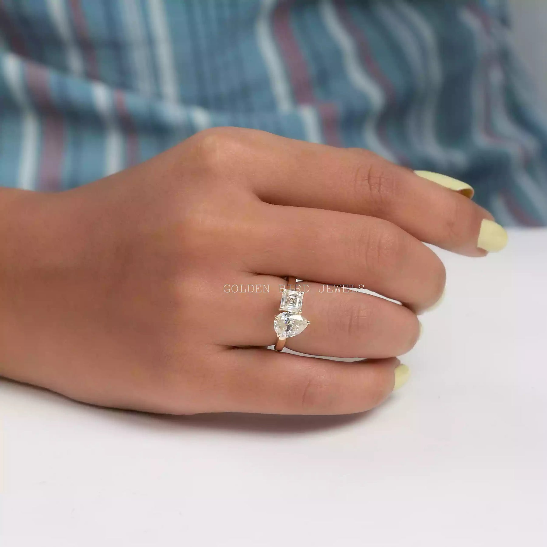In finger front view of toi et moi moissanite ring in yellow gold