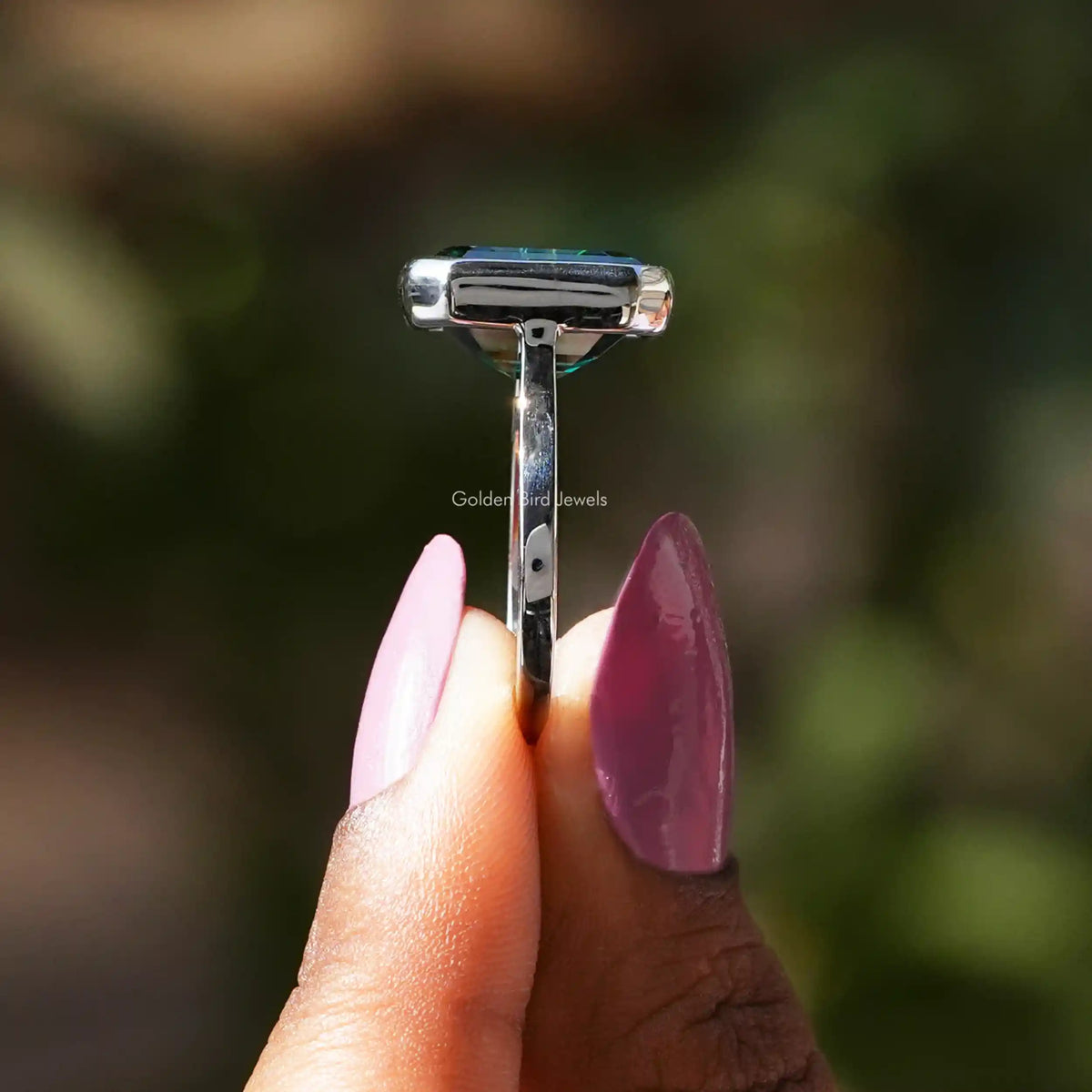 Side View of Green Emerald Cut Solitaire Ring In two fingers