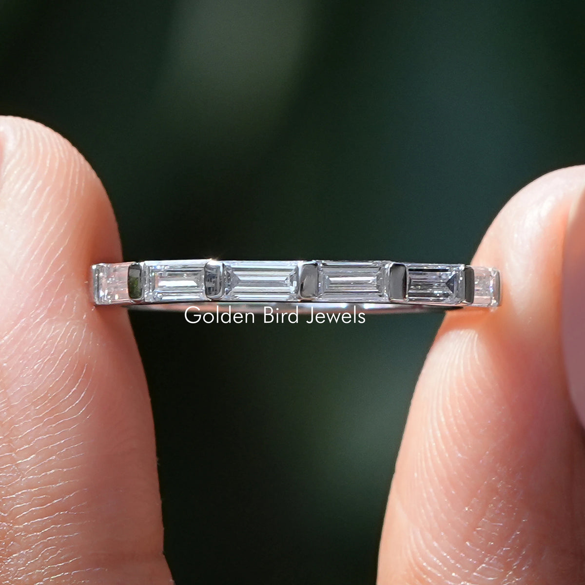 East West Baguette Diamond Wedding Band Held Between Fingers