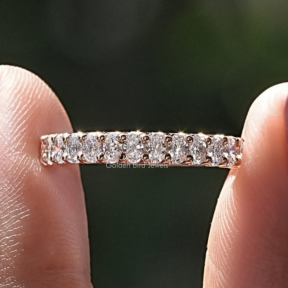 Oval Shaped Lab Diamond Half Eternity Band Held Between Fingers
