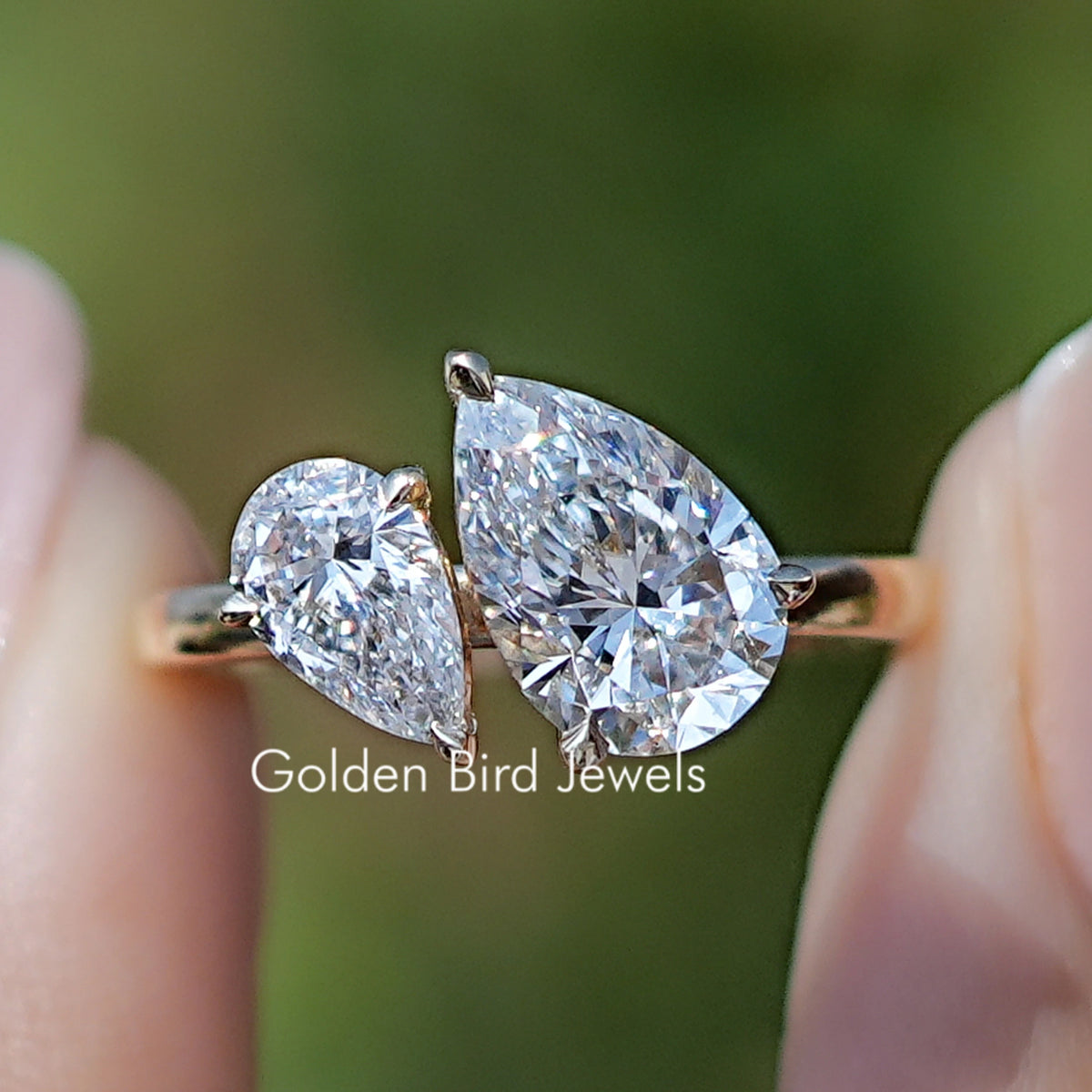 Pear Shaped Lab Diamond Two Stone Ring Held Between Fingers