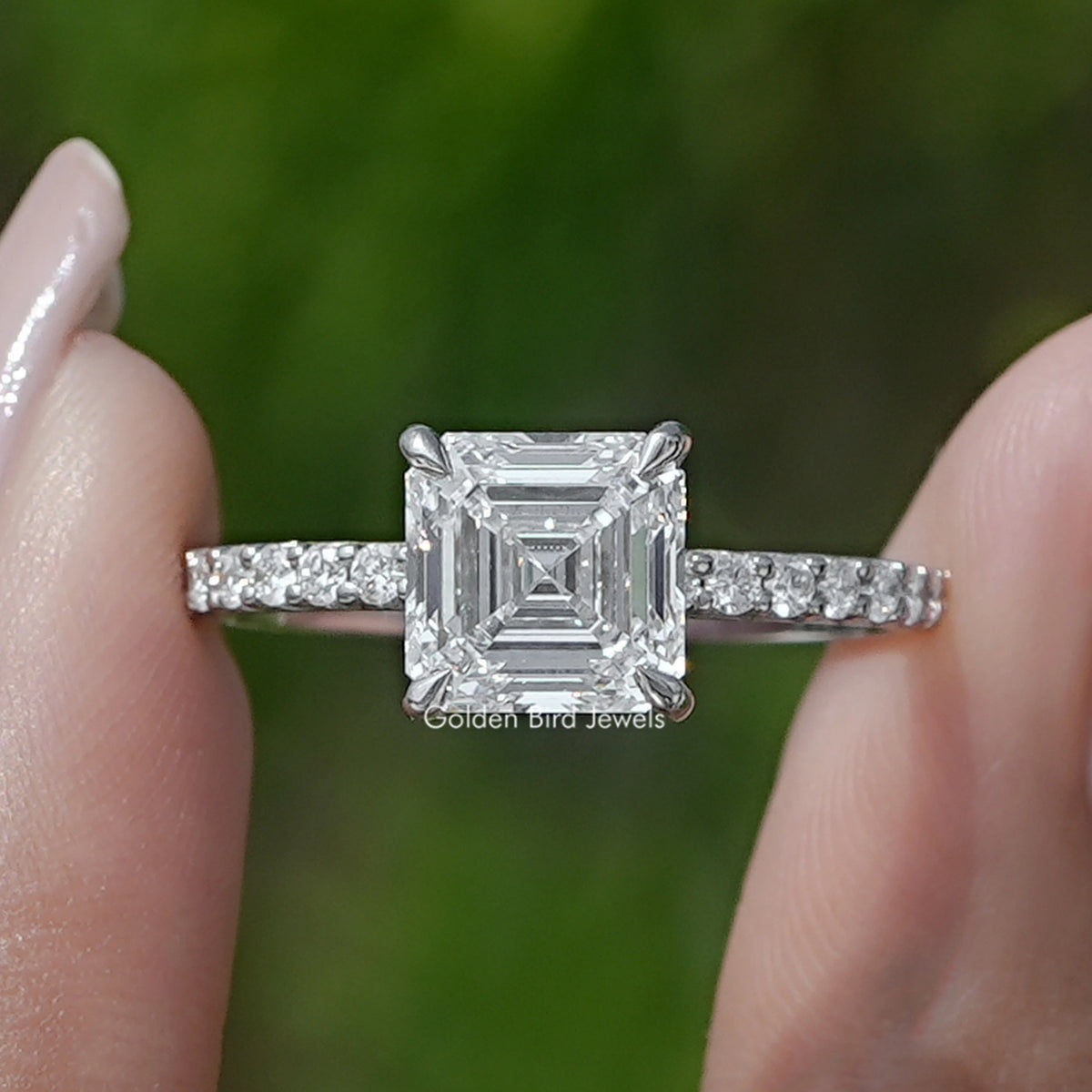 Square Emerald Cut Diamond Solitaire Ring Held Between Fingers