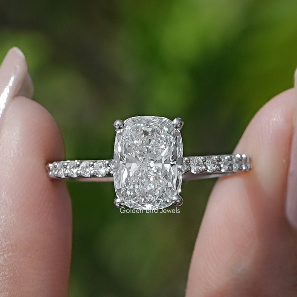 Cushion Cut Diamond Solitaire Ring Held Between Fingers