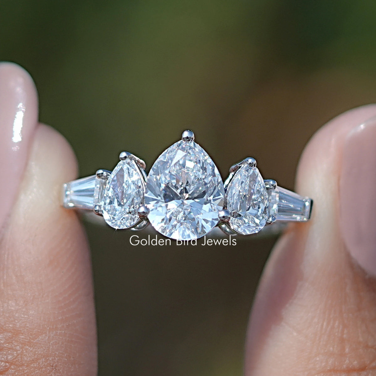 Five Stone Lab Grown Pear Cut Diamond Ring Held Between Fingers