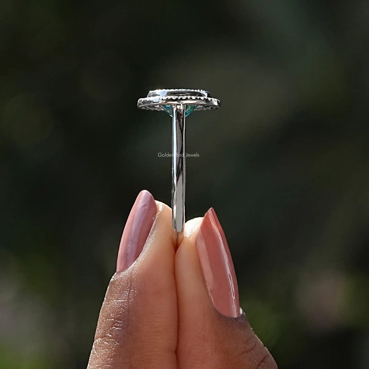 Side View of Blue Moissanite Bezel Set Halo Ring In two fingers