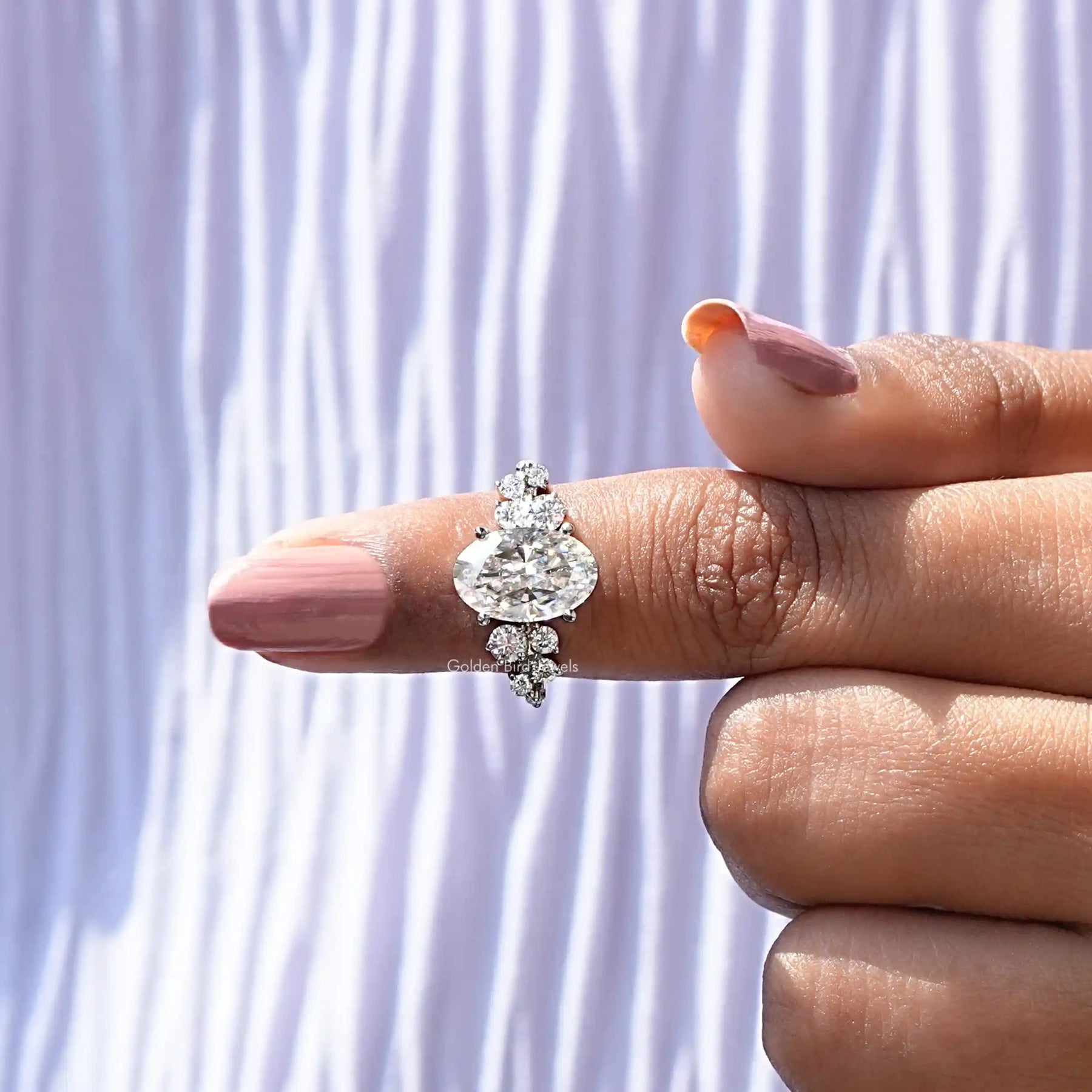 In finger view of solitaire oval moissanite wedding ring in secure setting