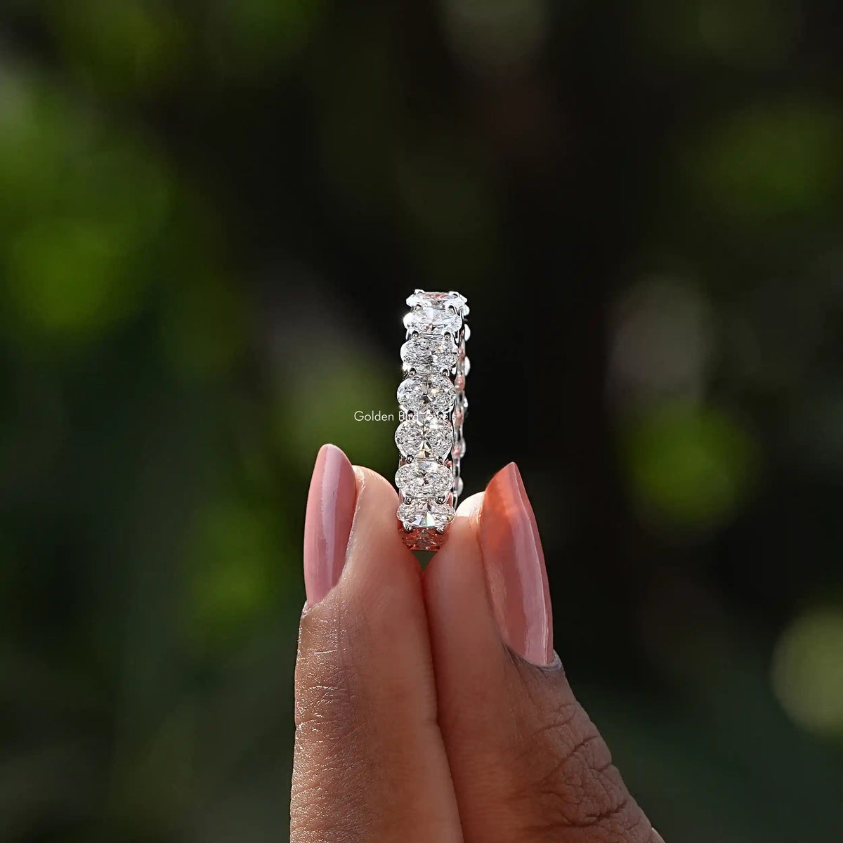 Side View of Oval Cut Diamond Wedding Band In two fingers