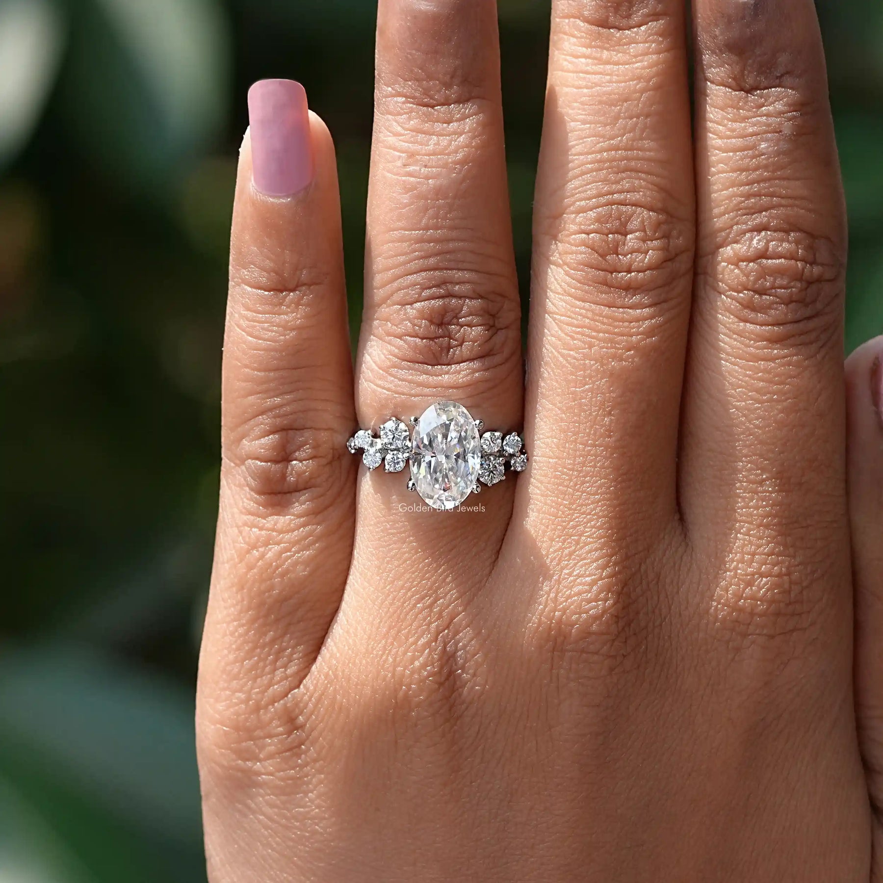 In finger view of oval shaped ring crafted with white side stones