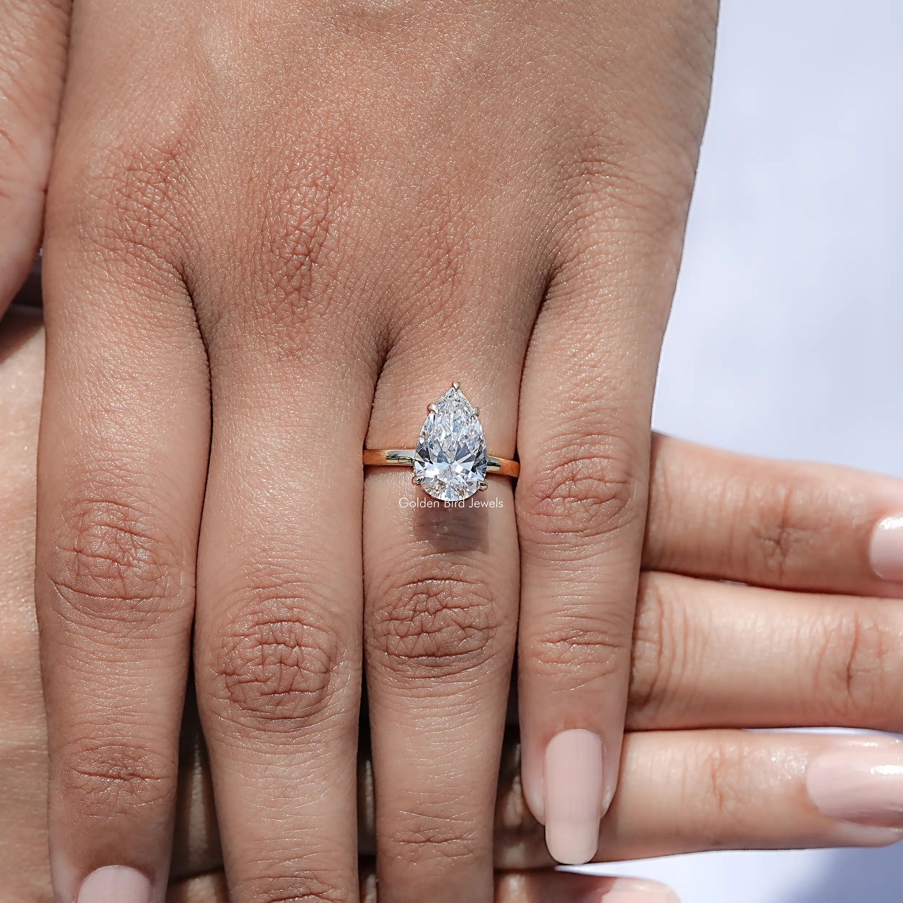 Top view of Pear Shaped Lab Diamond Halo Ring Held In Finger