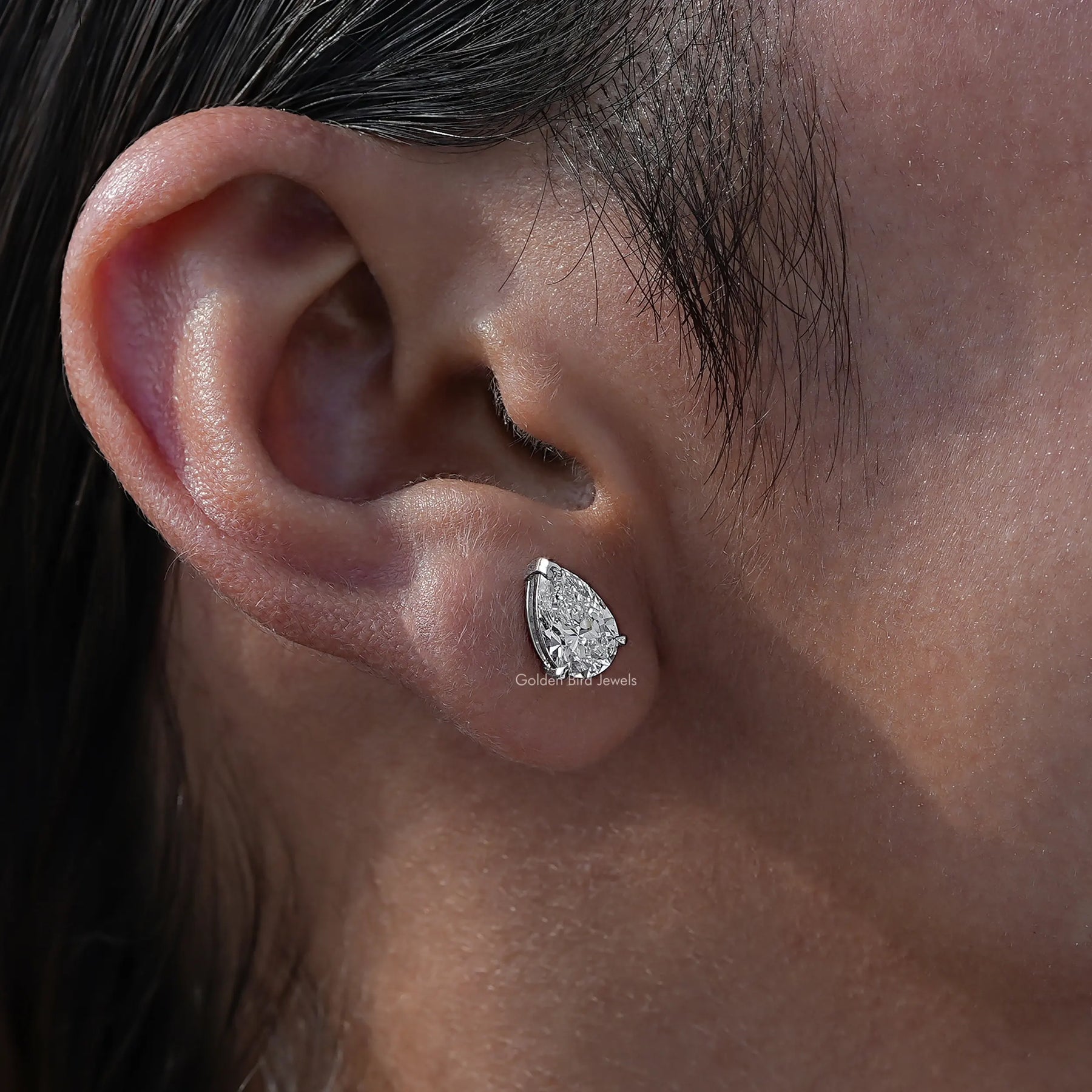Ear view of pear cut diamond stud earings with white stone