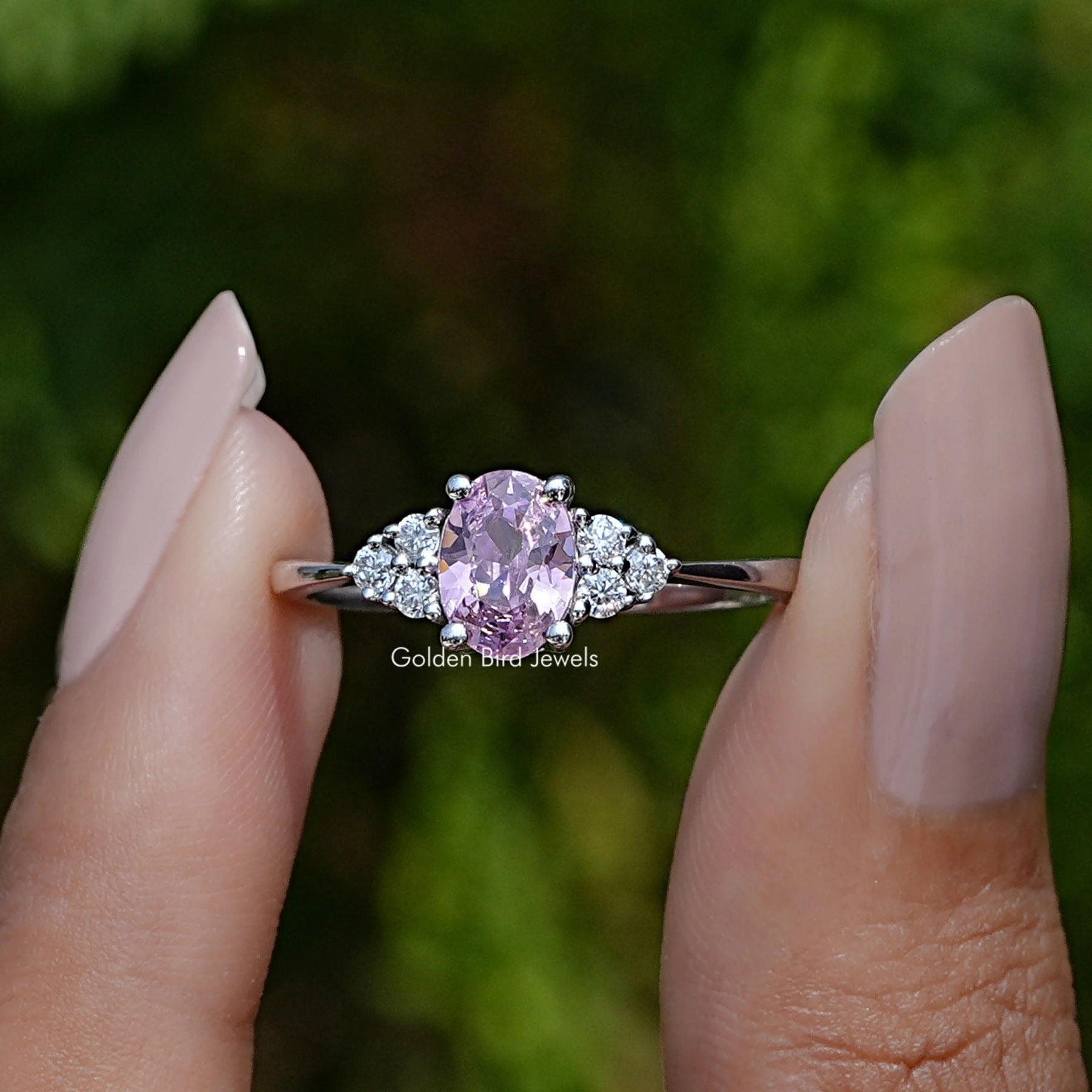 Front View of Oval Cut Gemstone Engagement Ring In two Fingers