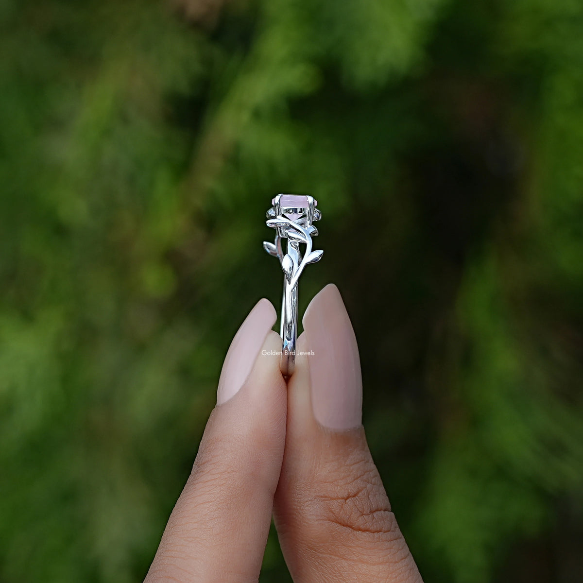 Side View of Round Gemstone Leaf Style Engagement Ring In two fingers