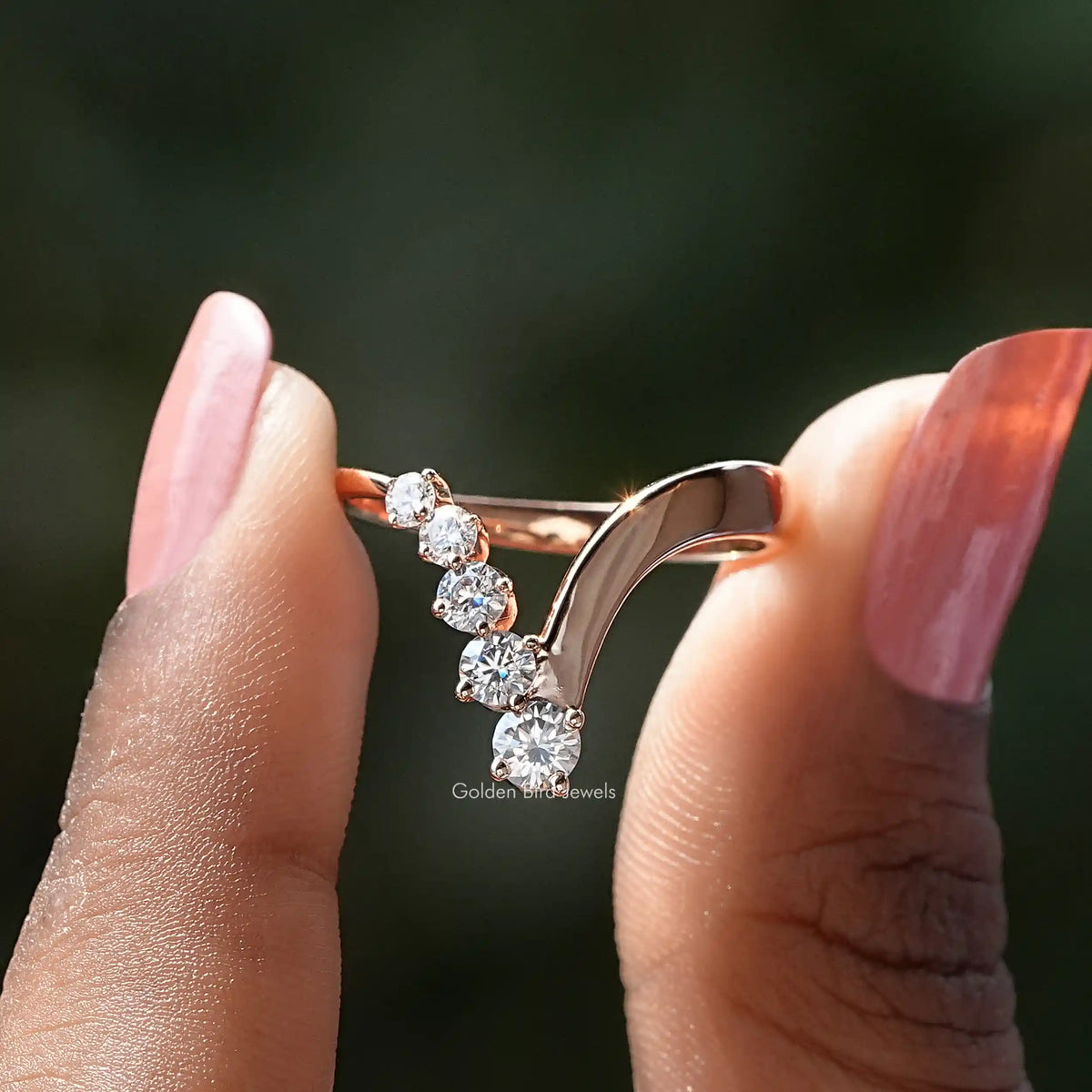 Two fingers holding the Round Cut Moissanite V Shaped Chevron Ring