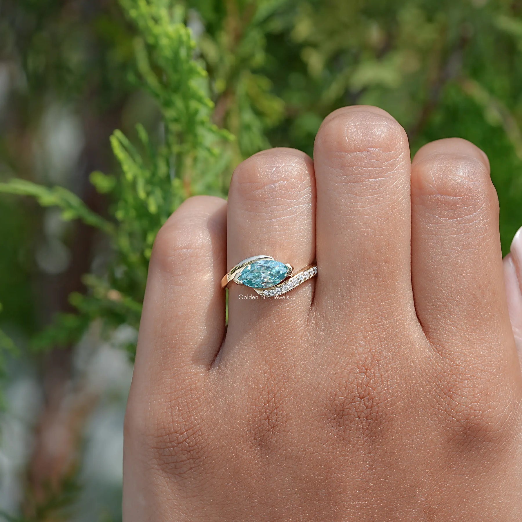 In finger front view of East West Blue Marquise Moissanite Bypass Ring
