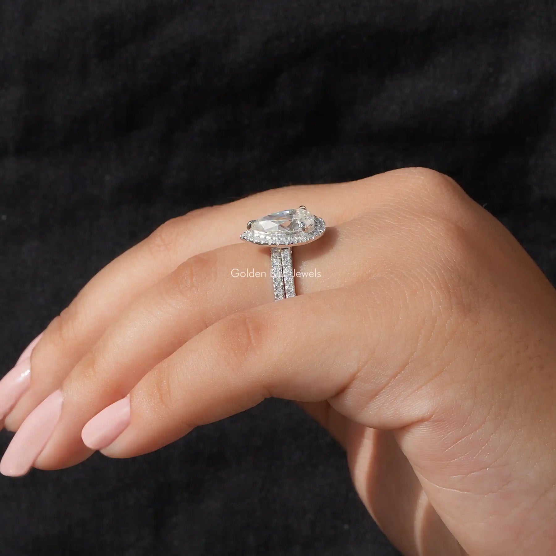 In finger side view of Pear and round cut moissanite wedding ring set with a secure setting