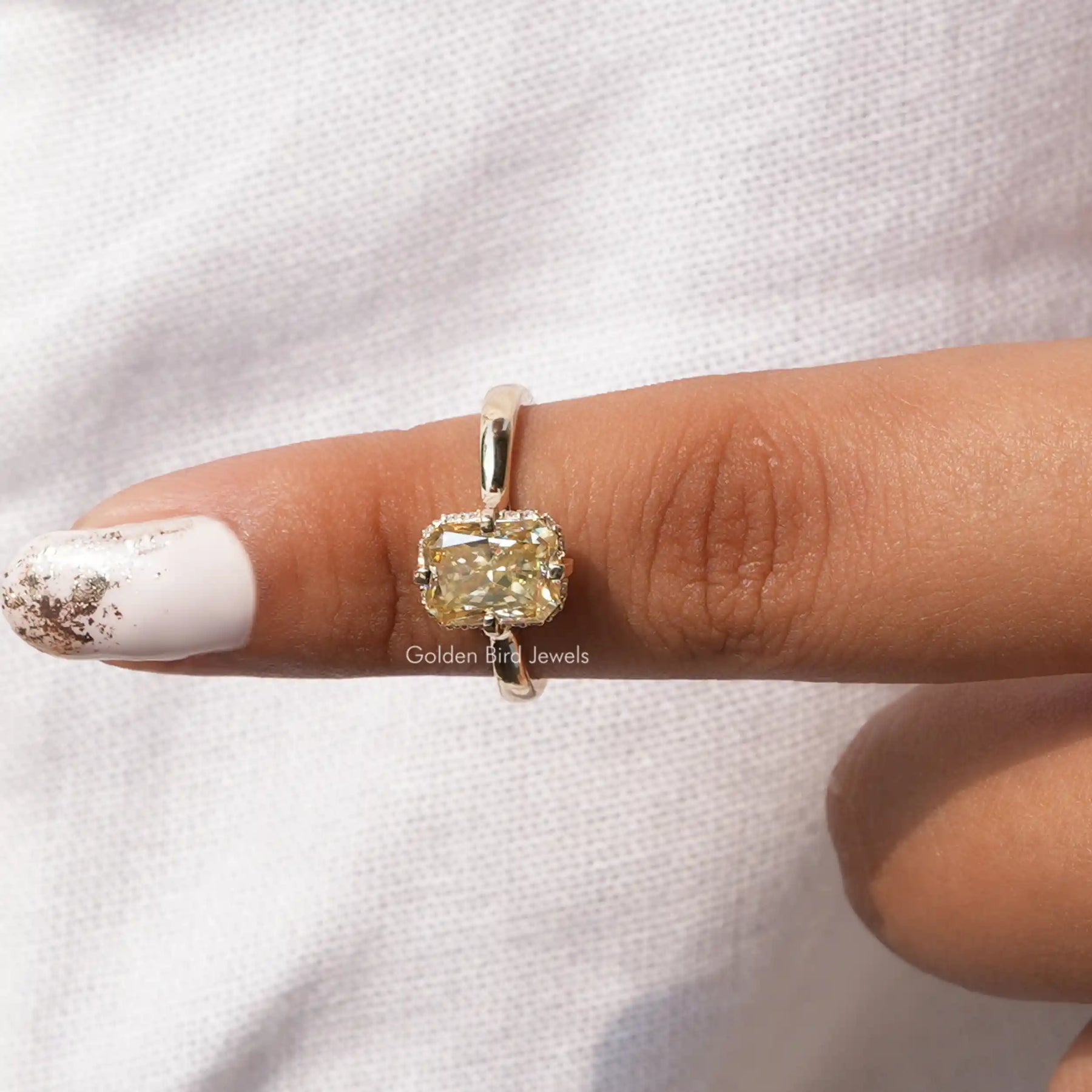 In front finger view of moissanite halo engagement ring