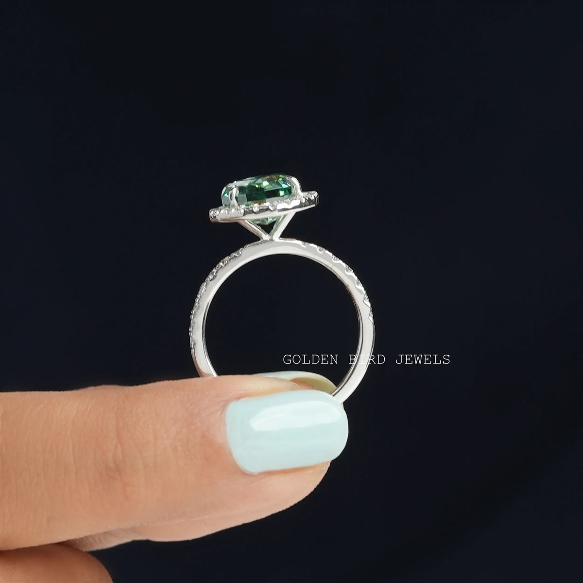 Back view of green oval cut moissanite ring in holding two fingers