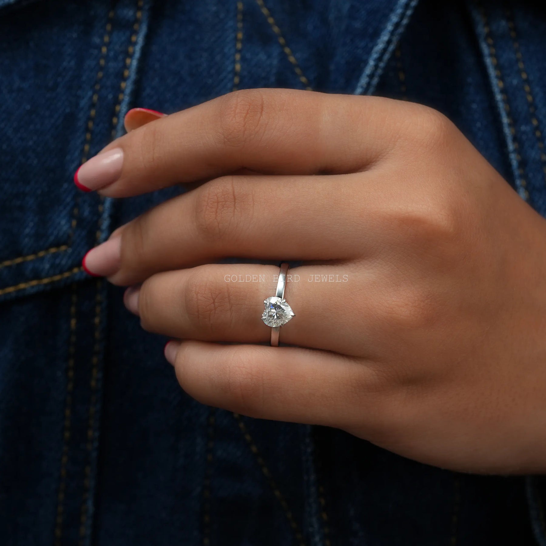 In finger view of colorless heart shaped moissanite solitaire ring