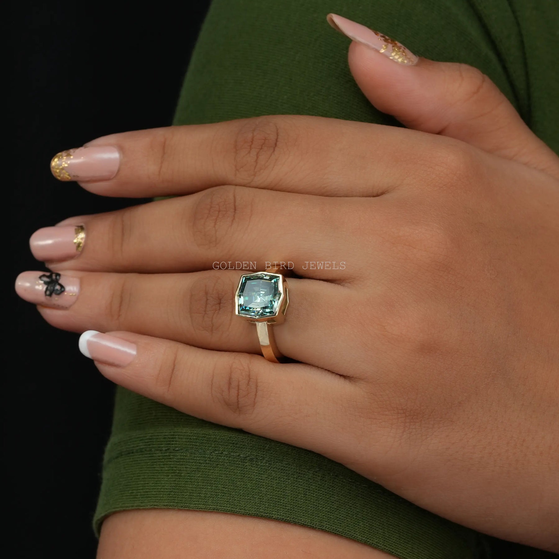 In Finger View of 3.85 Carat Blue Green Fancy Color Step Cut Cushion Shaped Moissanite BEzel Set Moissanite Engagement Ring
