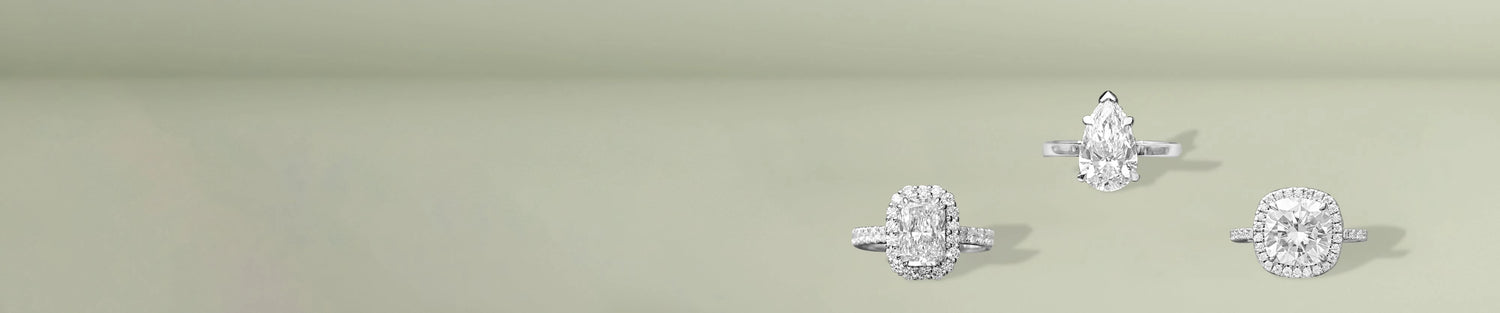 Lab grown diamond halo rings in elegant shapes displayed on soft green surface