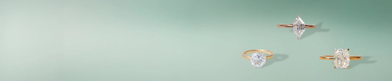 Moissanite solitaire engagement rings with elegant designs displayed on a green background 