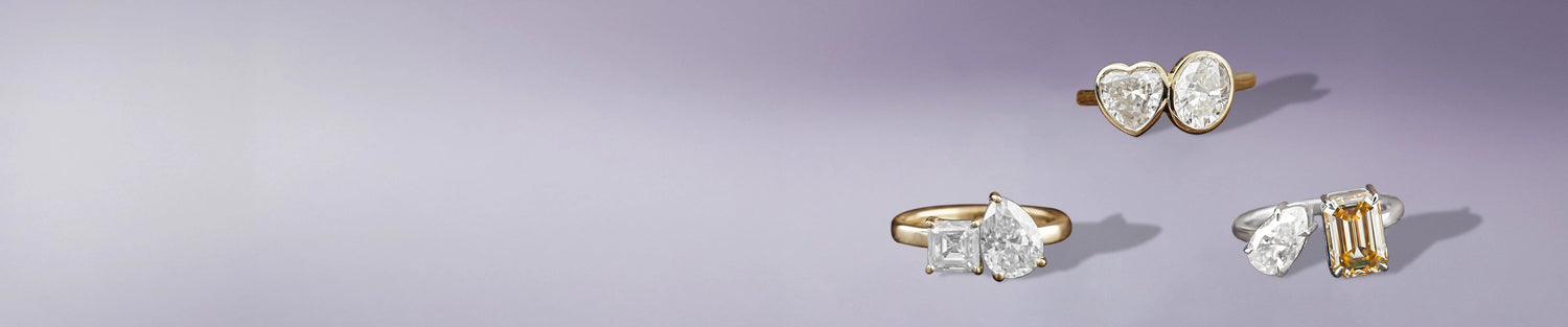 Two stone moissanite rings featuring heart, pear, oval, and emerald-cut gems in elegant styles