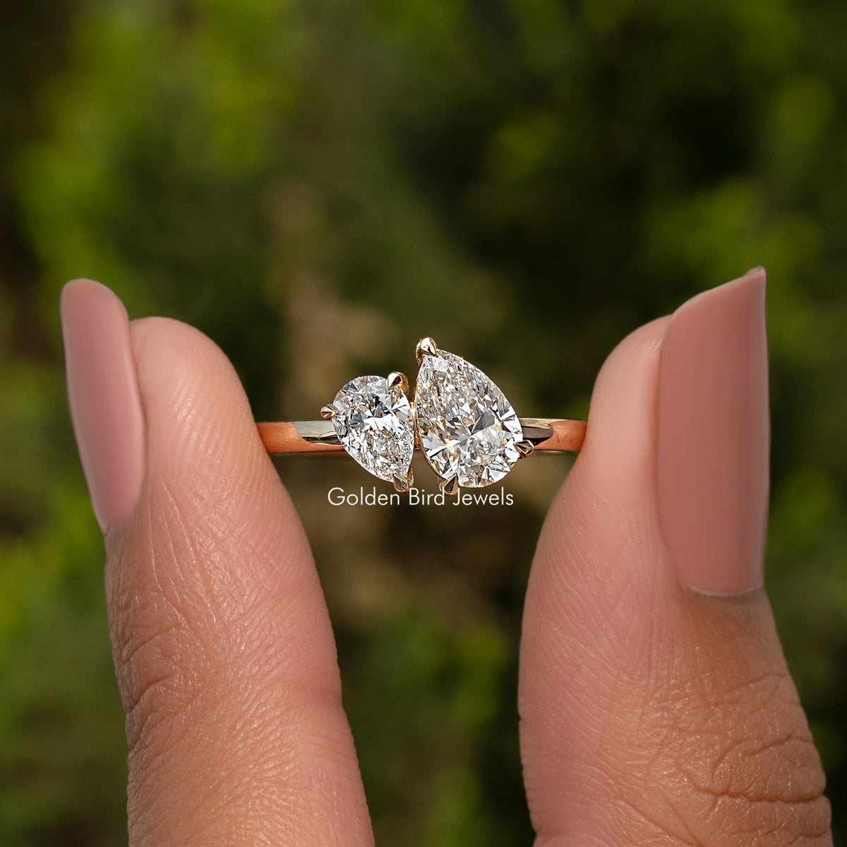 Pear Shaped Lab Diamond Two Stone Ring Held Between Fingers