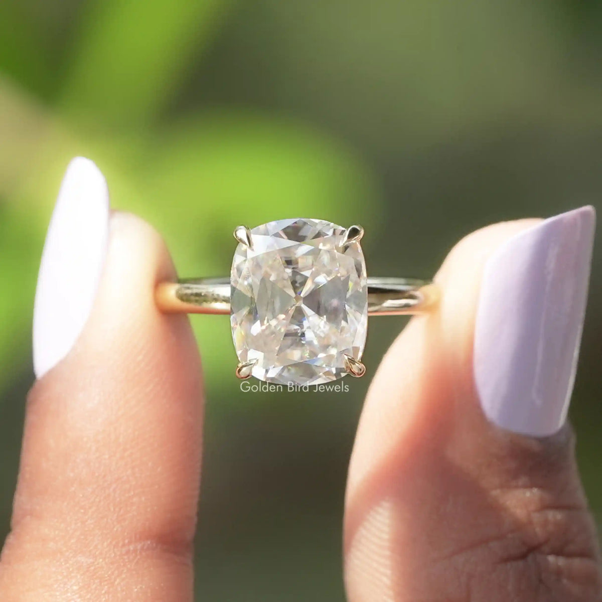 Two fingers holding the Old Mine Cushion Cut Moissanite Engagement Ring
