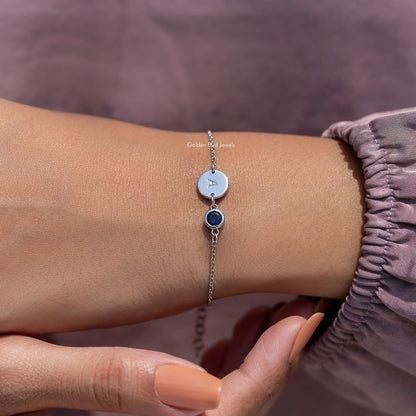 Sterling silver bracelet with letter A disc and blue round gemstone on wrist