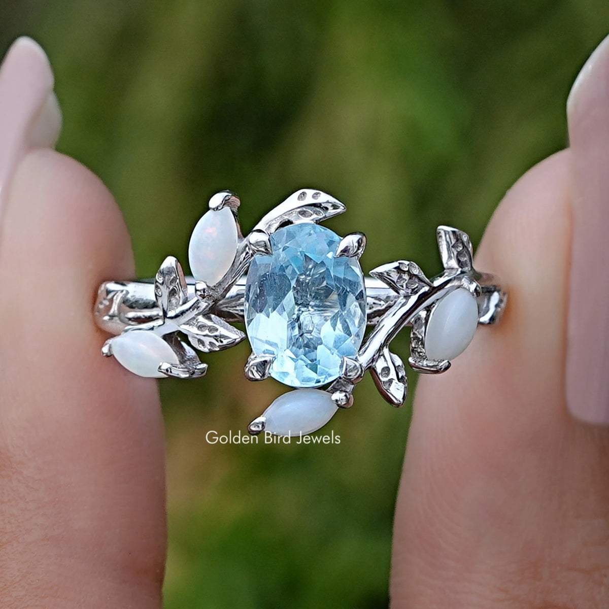 Front view of Aquamarine Oval Gemstone Leaf Style Accent Ring in two fingers 