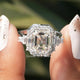 Two fingers holding the Moissanite Asscher Cut Halo Ring
