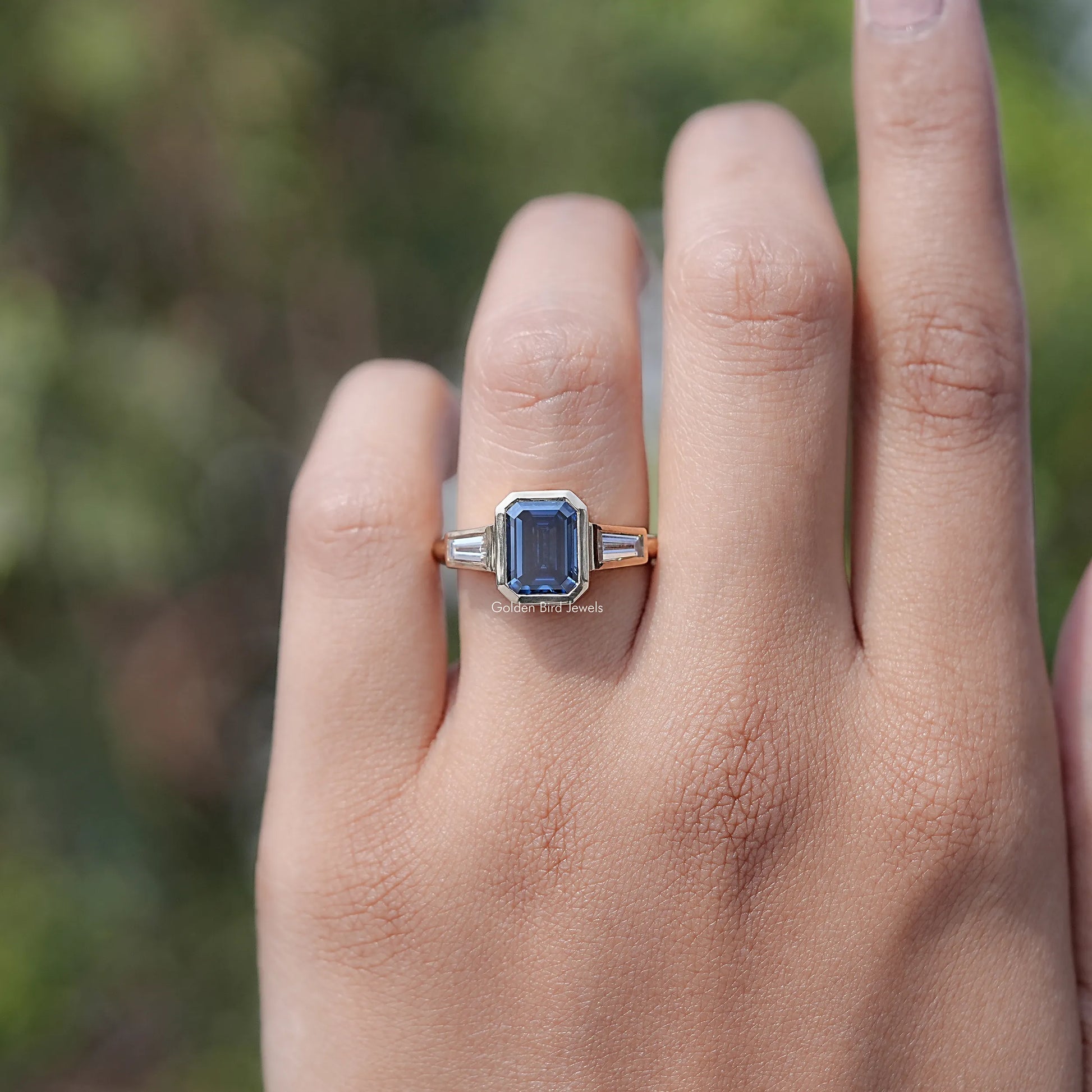 In finger view of Emerald Cut Moissanite Three Stone Engagement Ring		
