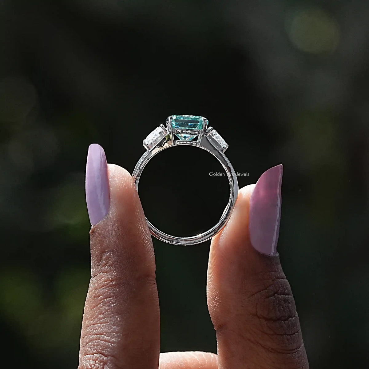 Back View of Blue Radiant Cut Moissanite Three Stone Ring In two fingers