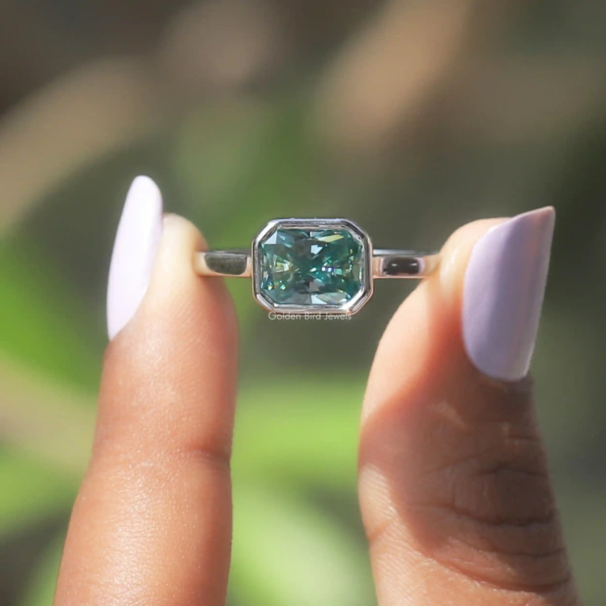 Two fingers holding the Radiant Cut Moissanite Engagement Ring