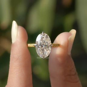 Two fingers holding the Ice Oval Moissanite Engagement Ring