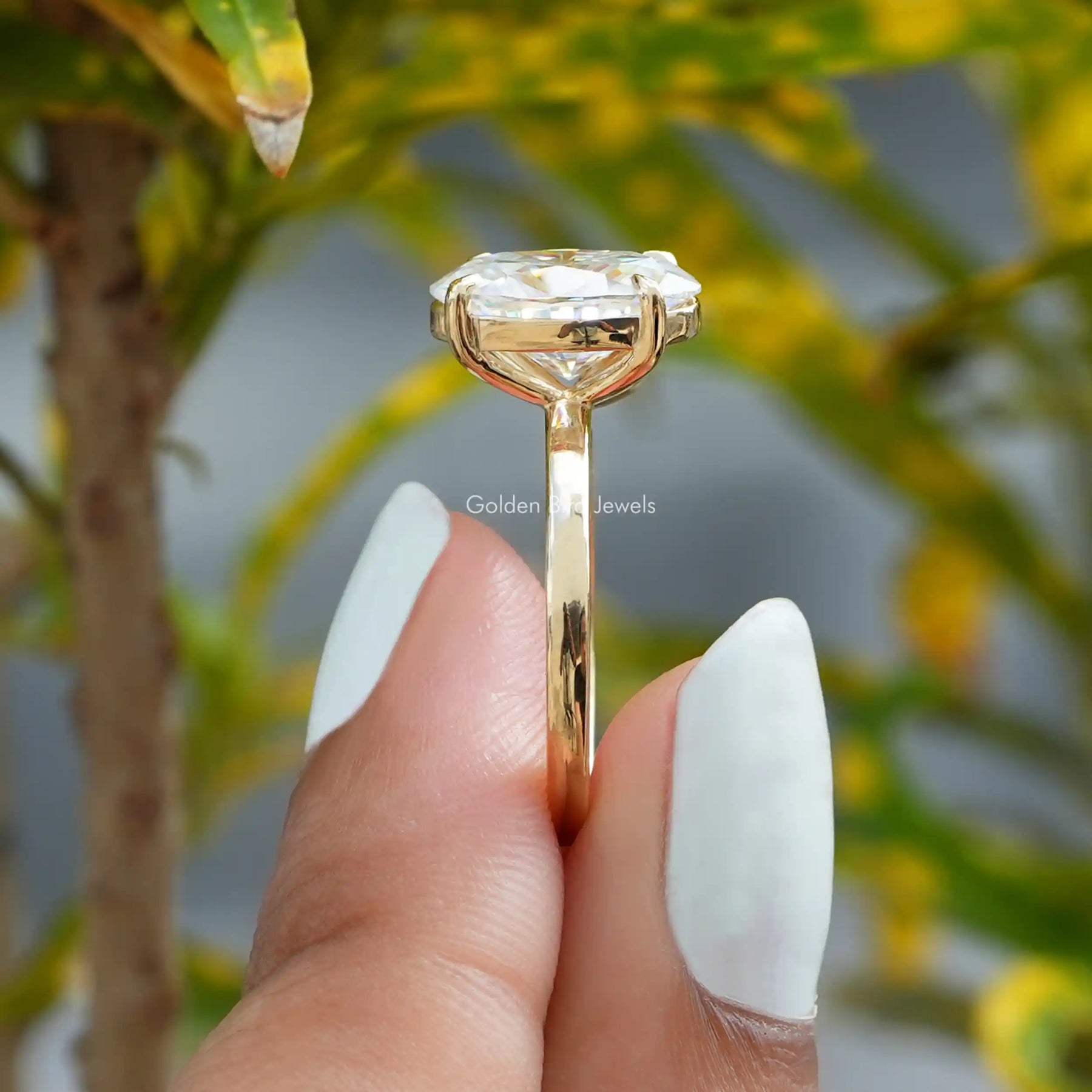 [In two finger side view of oval and round cut yellow gold moissanite ring]-[Golden Bird Jewels]
