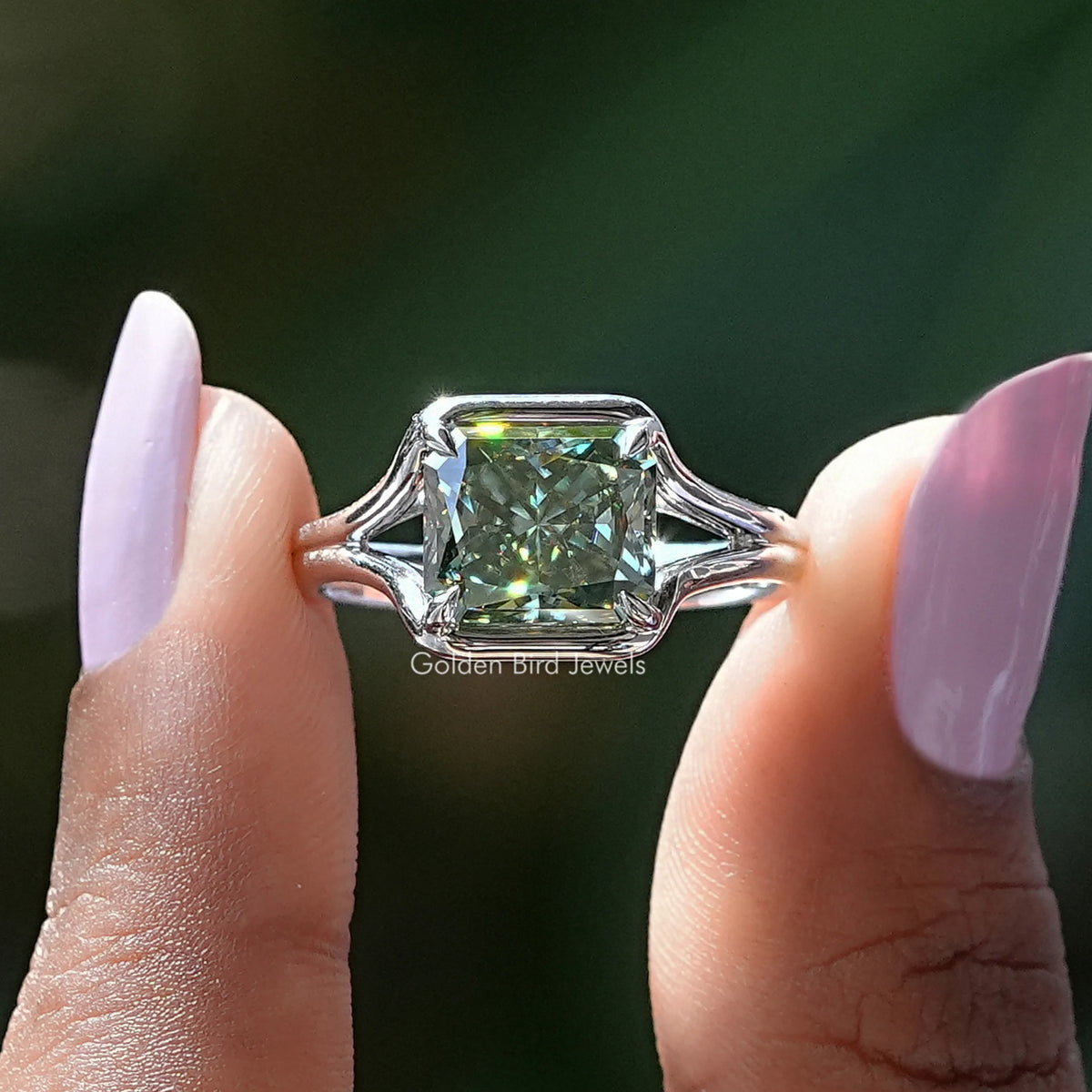 Two fingers holding the Green Radiant Cut Moissanite Solitaire Ring