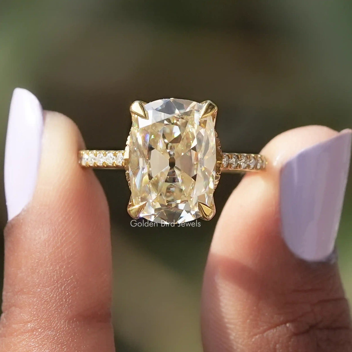 [In two finger front view of cushion cut moissanite engagement ring]-[Golden Bird Jewels]