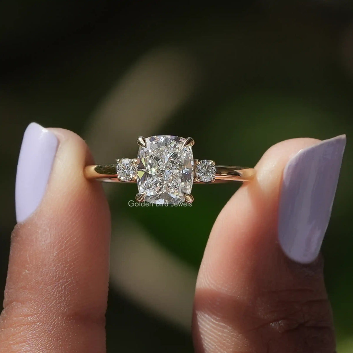 Cushion Cut Diamond Three Stone Ring held between two fingers