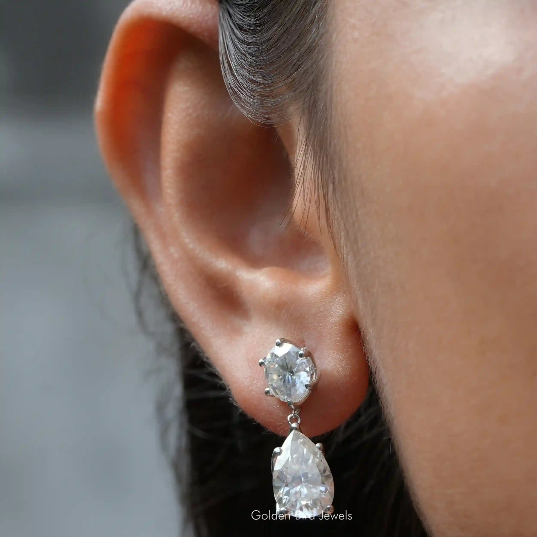 [In ear front view of colorless pear and round cut moissanite earrings in 14k white gold]-[Golden Bird Jewels]