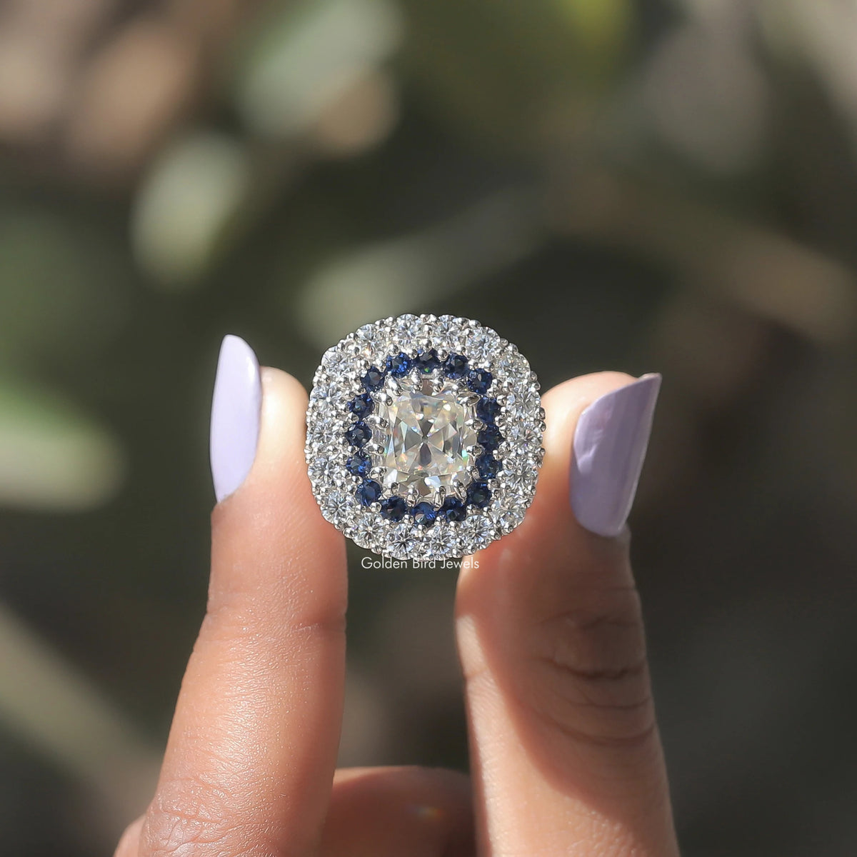 Two fingers holding the Double Halo Old Mine Cushion Cut Moissanite Ring